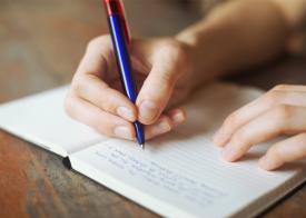 A person writing in a small notebook