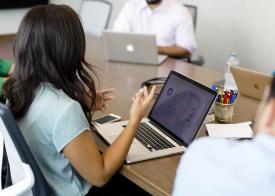 group of people talking at a table with their computers open