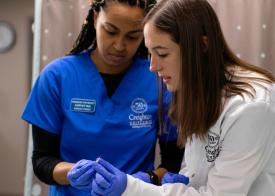 two female nurses from Creighton University College of Nursing looking at a needle