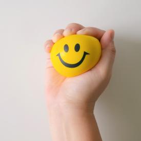 hand squeezing smiley face ball