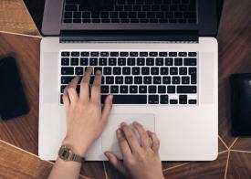 Hands typing on a laptop computer